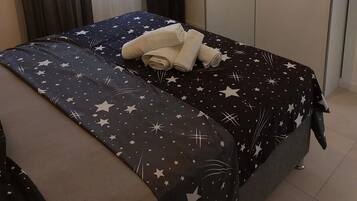 A bed with a star-patterned bedspread and neatly folded towels.
