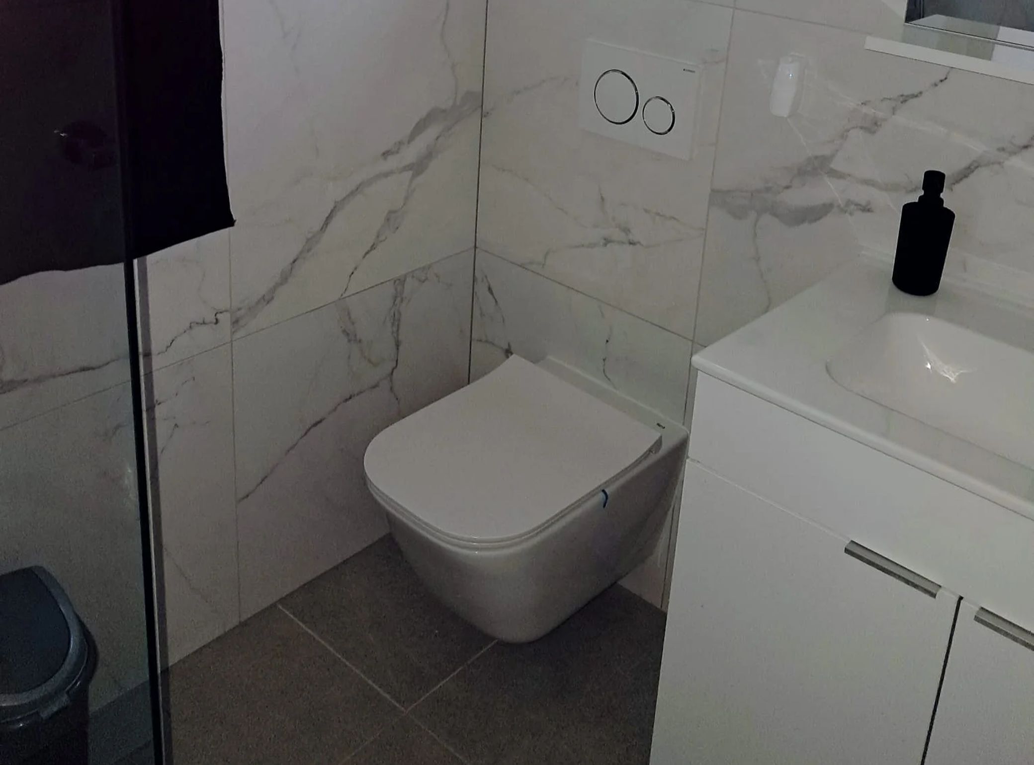 A bathroom with a toilet, a sink, and a mirror.