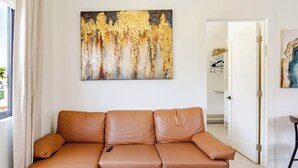 A living room with a brown leather sofa, a wooden coffee table, and a painting on the wall. - Newly Built Modern Guest House • Cozy w/ Kitchen (Los Angeles)