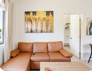 Ein Wohnzimmer mit einem braunen Ledersofa, einem Holztisch und einem Bild an der Wand.