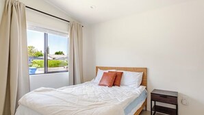 A bedroom with a bed, a nightstand, and a window with curtains. - Newly Built Modern Guest House • Cozy w/ Kitchen (Los Angeles)