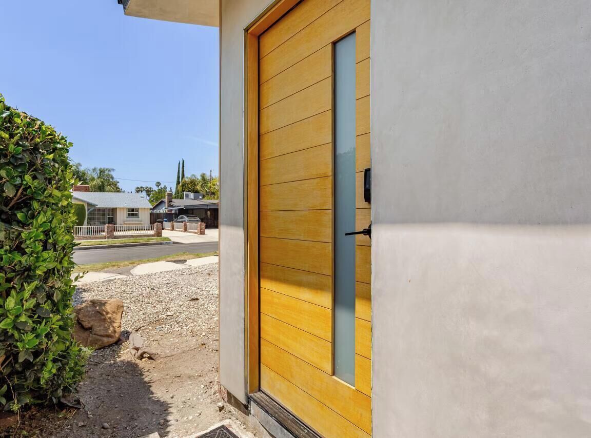 Un edificio residencial con una puerta amarilla, una ventana y un pequeño escalón que conduce a la entrada.