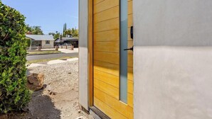A residential building with a yellow door, a window, and a small step leading to the entrance. - Newly Built Modern Guest House • Cozy w/ Kitchen (Los Angeles)