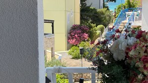 Ein Balkon mit Blick auf ein Wohngebiet, darunter Häuser mit roten Ziegeldächern und einer blauen Treppe.