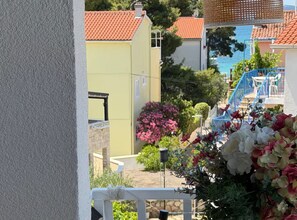 A balcony with a view of a residential area, including houses with red-tiled roofs and a blue staircase. - Tina Sea View Retreat (Vodice)