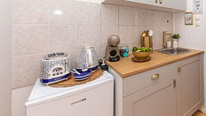 Eine Küche mit weißen Schränken, einer Holzarbeitsplatte, einem Toaster, einem Wasserkocher, einer Fruchtschale und einem Spülbecken.