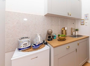A kitchen with white cabinets, a wooden countertop, a toaster, a kettle, a bowl of fruit, and a sink. - Tina Sea View Retreat (Vodice)