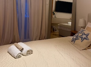 A hotel room with a bed, a TV, a lamp, and a window with curtains. - Tina Sea View Retreat (Vodice)