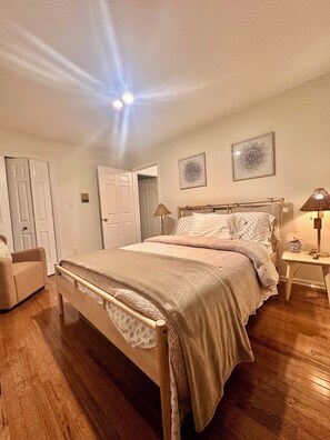 A bedroom with a bed, a chair, a bedside table with a lamp, and a door. - Normandy H. a charming house in silver spring. 5 min from The Adventist Hospital (Silver Spring)
