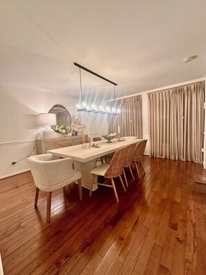 A dining area with a long wooden table, six chairs, a chandelier, and a large mirror. - Normandy H. a charming house in silver spring. 5 min from The Adventist Hospital (Silver Spring)