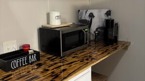 Una cocina con barra de café, microondas y cafetera.