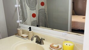 Un baño con lavamanos, espejo y cortina de ducha a rayas.