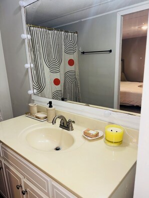 Ein Badezimmer mit Waschbecken, Spiegel und einer Duschvorhang mit Streifenmuster.