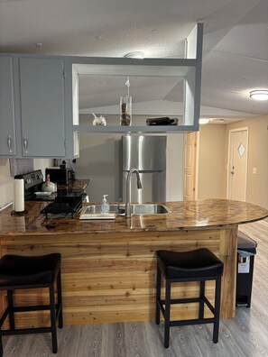 A modern kitchen with a central island, stainless steel appliances, and wooden flooring. - Newly renovated 2 bedroom mobile home in peaceful Rocky Mount with AC (Rocky Mount)