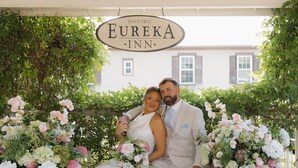 Ett par sitter under en skylt med texten ”EUREKA INN”.