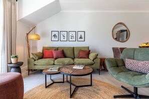 A modern living room with a green sofa, two round coffee tables, a floor lamp, and framed artwork on the wall. - Neo-African apartment at the entrance of Durbanville wine route (Cape Town)