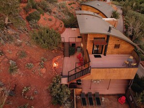 Ein modernes, mehrgeschossiges Haus mit gewölbter Dachform, einer Terrasse und einem Feuerkorb.