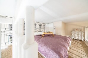 A bedroom with a bed, a dresser, a mirror, and a view of a building. - Kraków Podgórze Incognito Studio — Wawel & Old Town Nearby (Kraków)