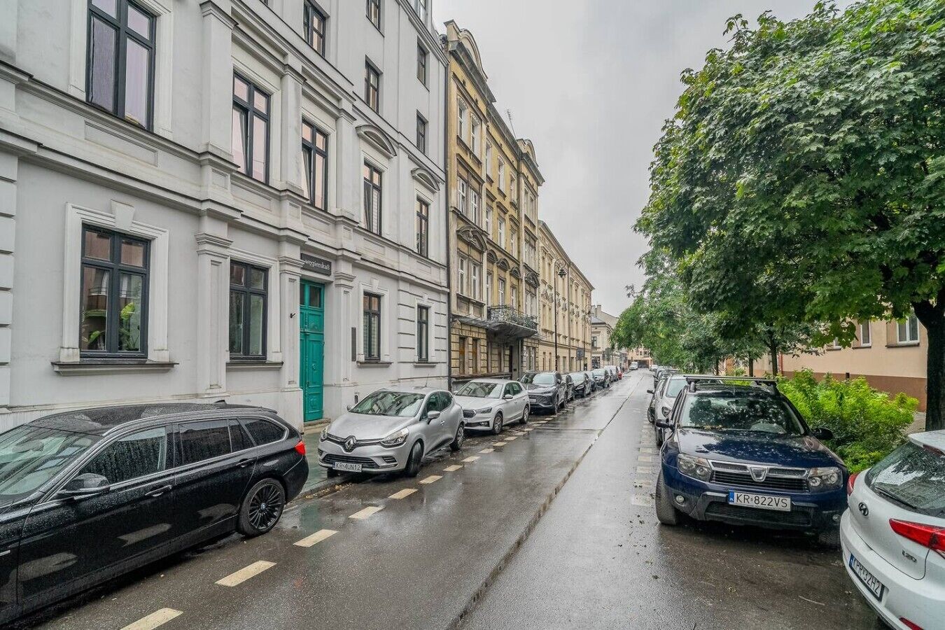 Een straat met geparkeerde auto's en gebouwen met meerdere verdiepingen en ramen.