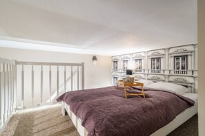 A bedroom with a bed, a nightstand, a lamp, and a decorative headboard. - Kraków Podgórze Incognito Studio — Wawel & Old Town Nearby (Kraków)