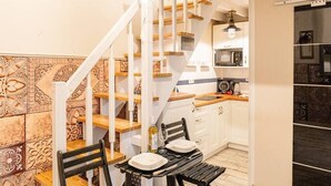 Une cuisine avec un coin repas, un escalier en bois et une horloge.
