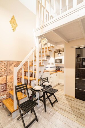 A kitchen with a dining area, wooden staircase, and a clock. - Kraków Podgórze Incognito Studio — Wawel & Old Town Nearby (Kraków)