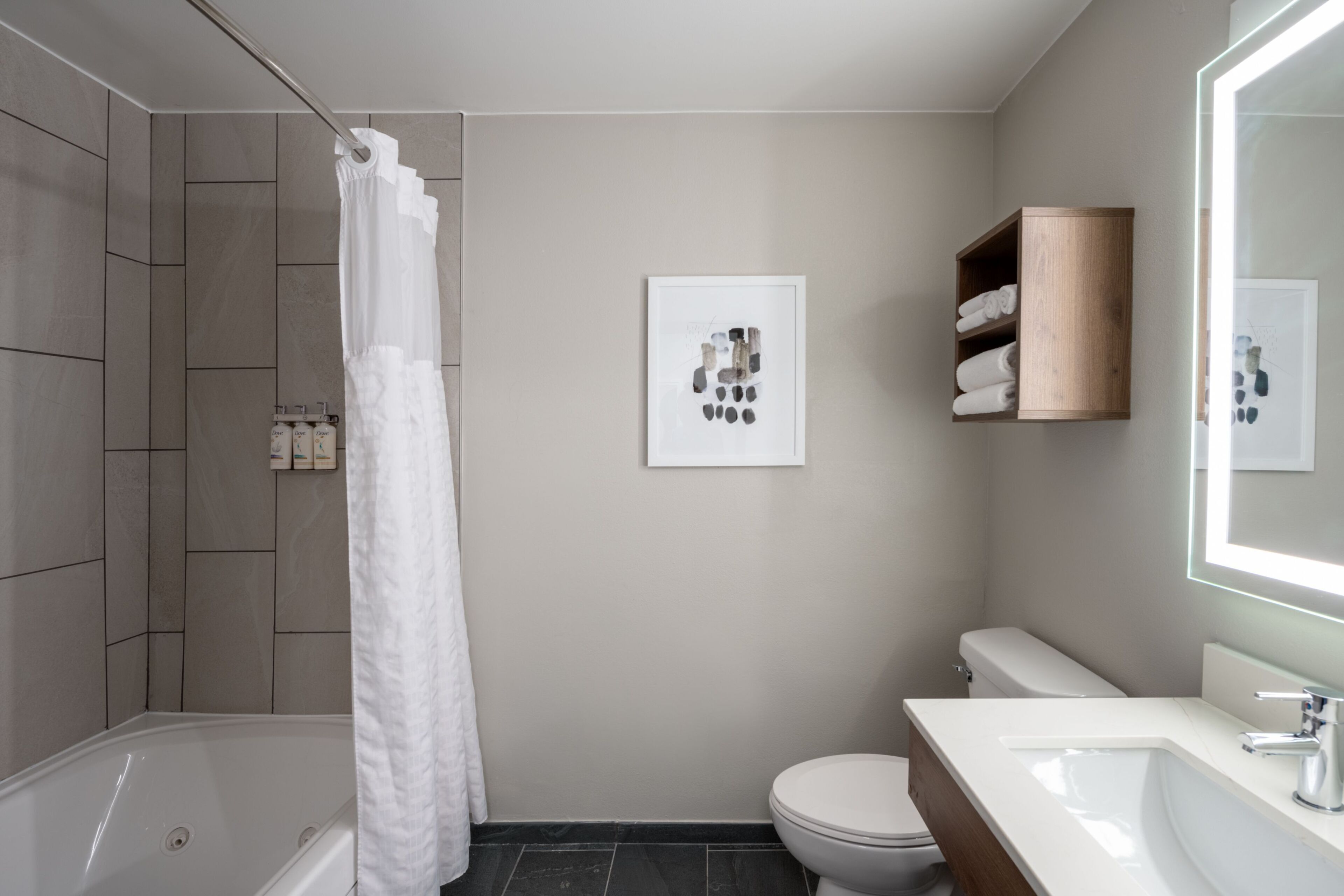 Moderni kylpyhuone, jossa on kylpyamme, wc ja suihkutila.