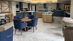 A modern hotel lobby with a central island, seating area, and a kitchenette. - Studio Suite w/ Jetted Tub | Free Breakfast! (West Des Moines)