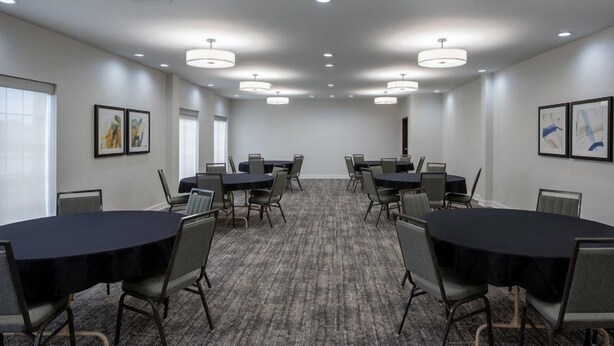 A conference room with multiple tables and chairs, large windows, and ceiling lights. - Suite w/ Fireplace & Full Kitchen | Free Breakfast (West Des Moines)