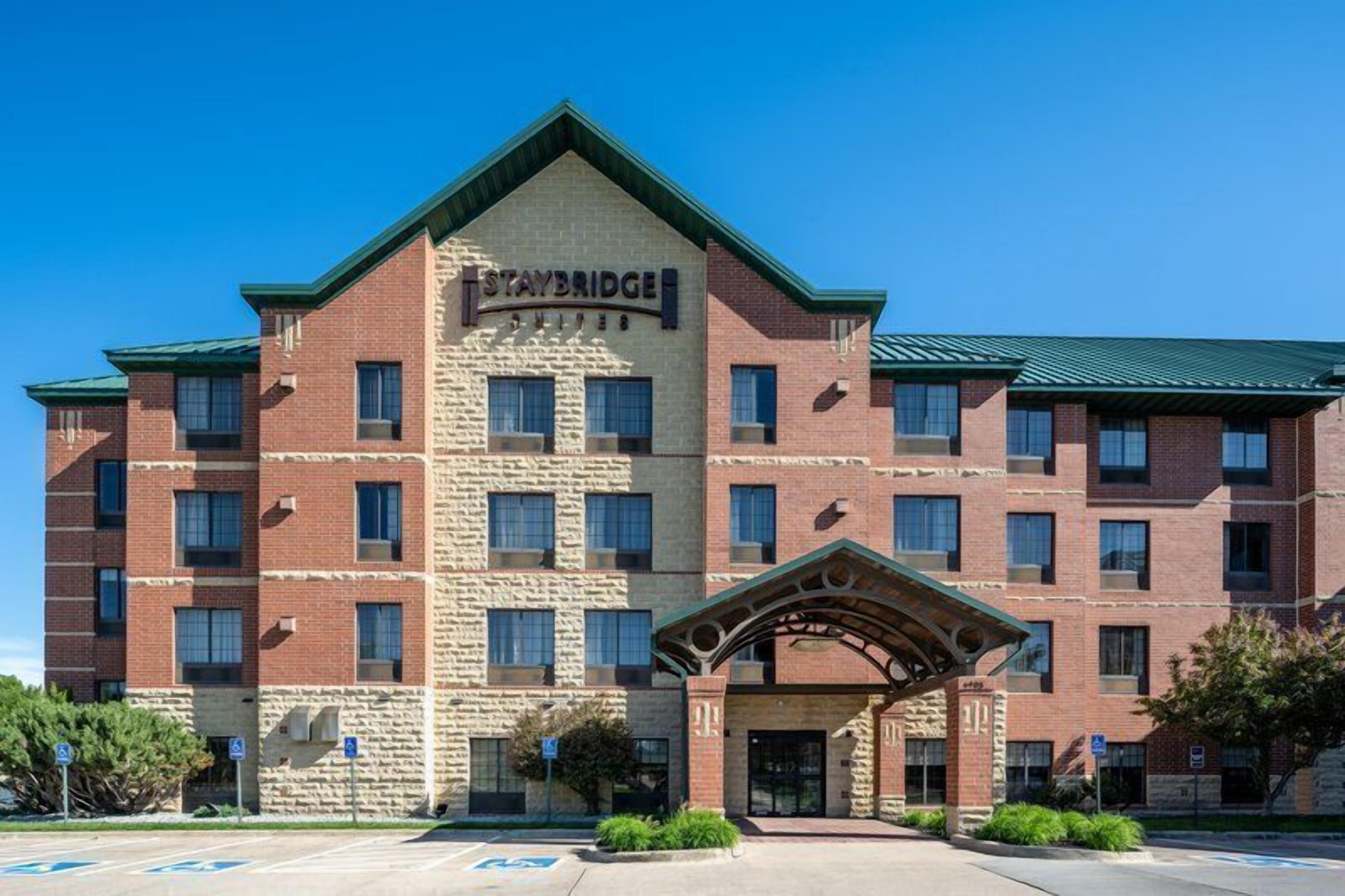 Un hôtel Staybridge avec une façade en briques, de nombreuses fenêtres et une entrée abritée.