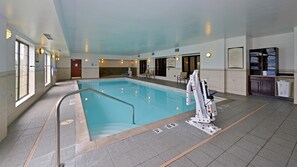 An indoor swimming pool with clear water, marked depth lines, and a lifeguard stand.