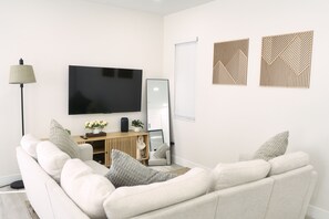 Ein modernes Wohnzimmer mit Flachbildfernseher, einem Stehspiegel und Wanddekoration.