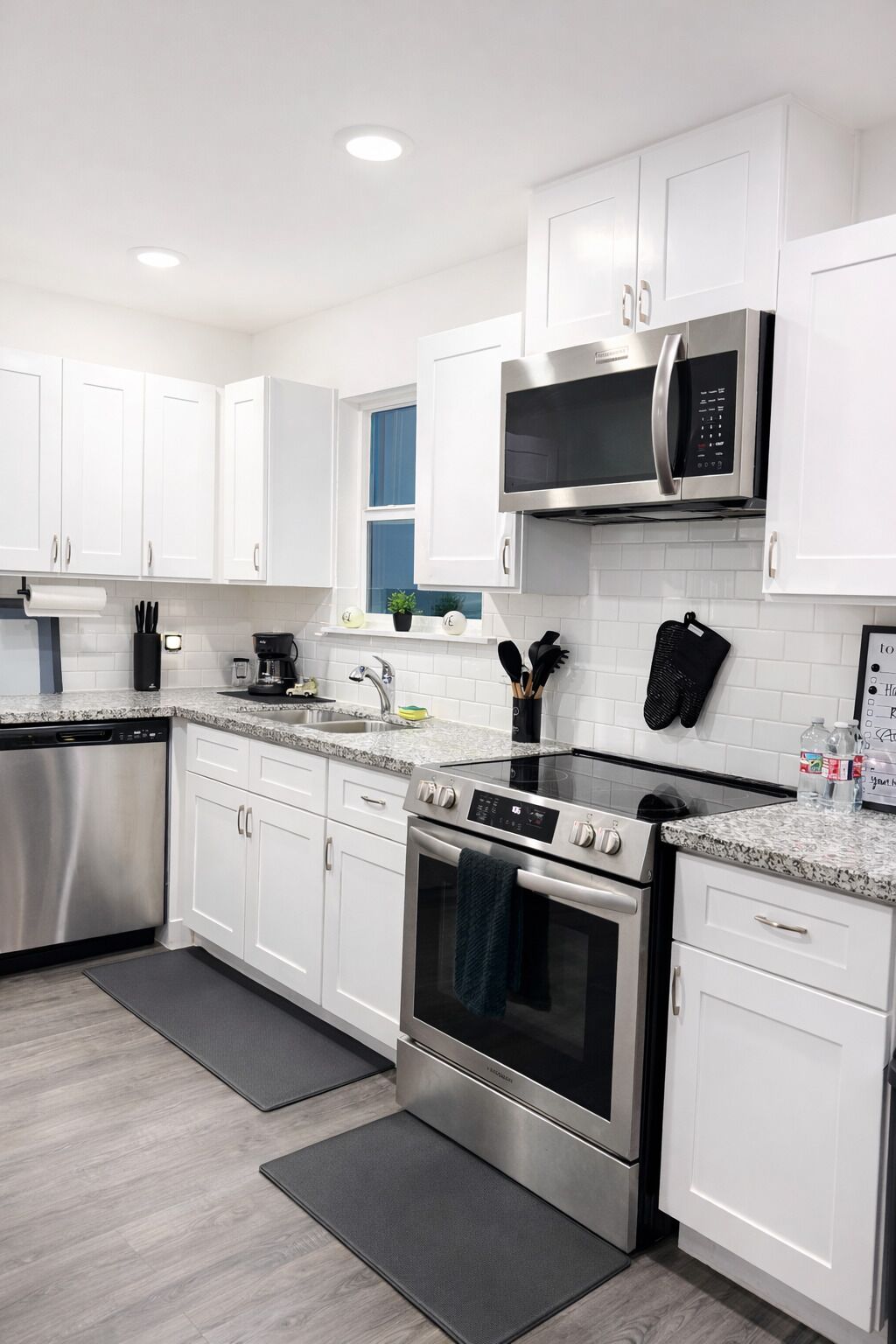 A modern kitchen with white cabinets, stainless steel appliances, and a granite countertop.