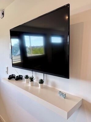 A flat-screen TV mounted on a white wall with a shelf below.
