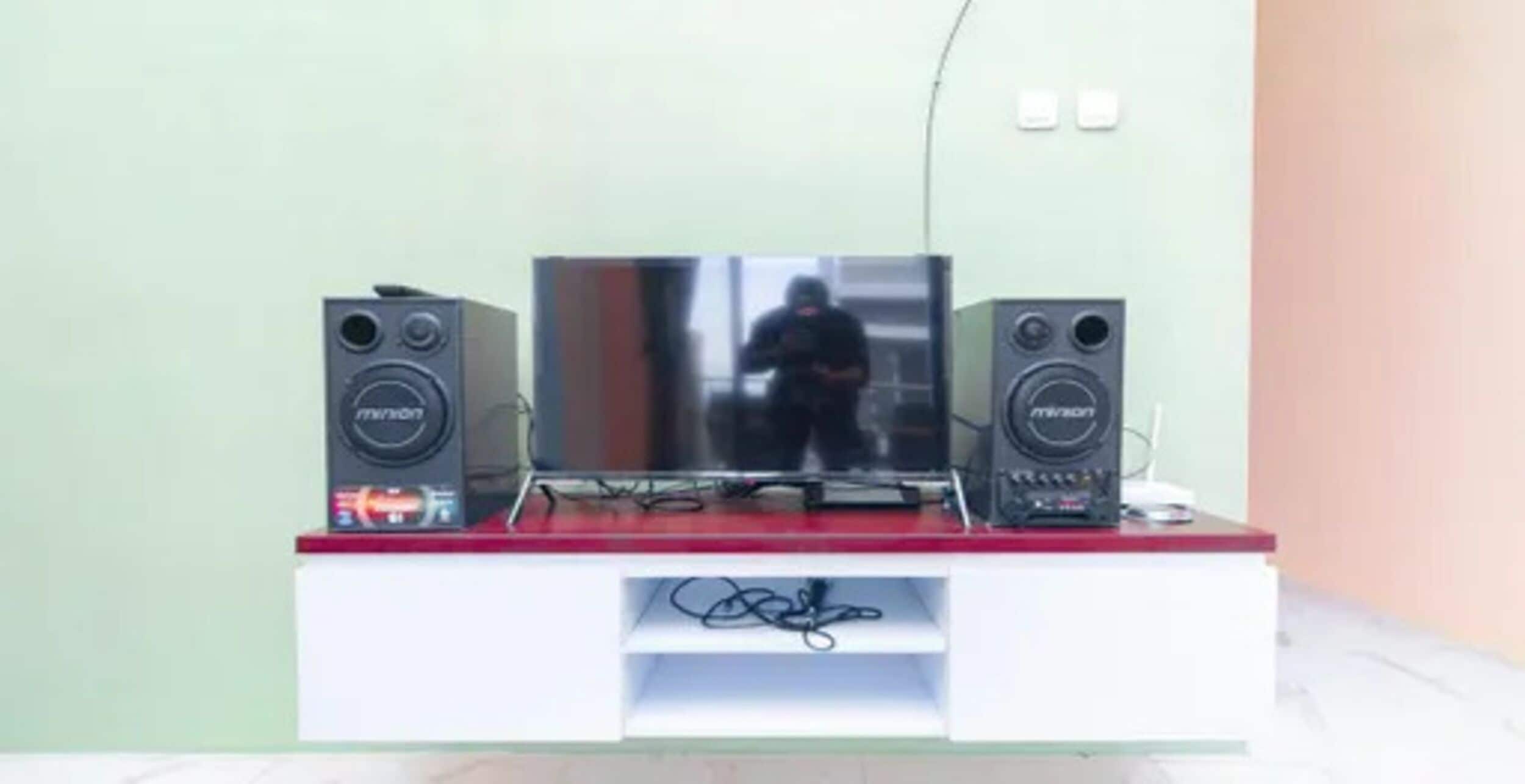 A television on a white stand with two speakers on either side.