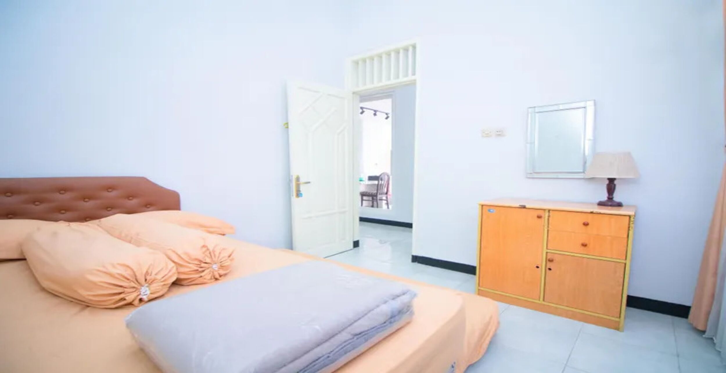 Un dormitorio con cama, cómoda, espejo y puerta que da a otra habitación.