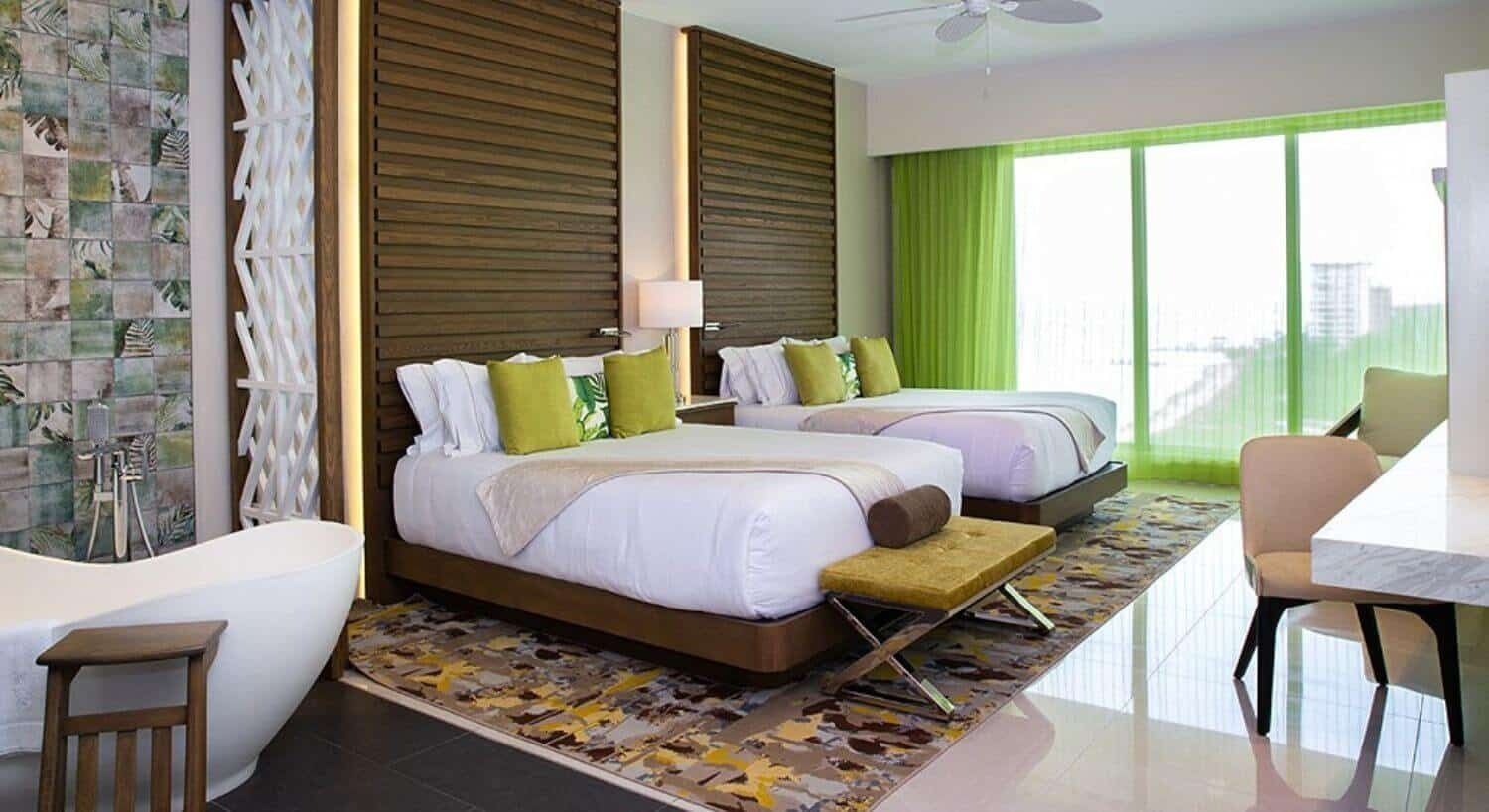 Quarto de hotel com uma cama grande, uma cama extra, banheira e área de refeições.