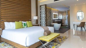 Quarto de hotel moderno com uma cama grande, uma escrivaninha, uma cadeira, um banheiro e um espelho.