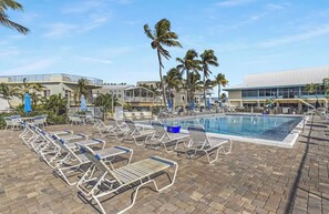 A pool area with lounge chairs and palm trees. - New Construction in Outdoor Resorts Long Key! (Layton)