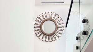 Una escalera de madera con peldaños que conducen a un rellano, donde un espejo circular con marco tejido está fijado a la pared.
