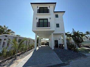 A modern two-story building with a covered walkway and a poolside area. - New Construction in Outdoor Resorts Long Key! (Layton)