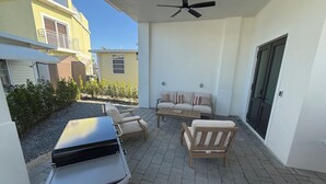 Un patio exterior con una parrilla, zona de estar y ventilador de techo.