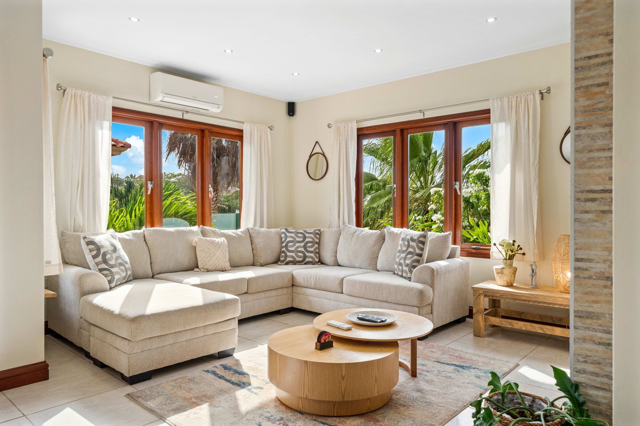 A modern living room with a sectional sofa, a round coffee table, and large windows with curtains.
