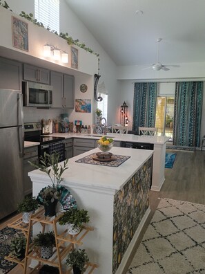 A modern kitchen with a central island, built-in appliances, and decorative plants. - Peaceful one bedroom Villa with Mediterranean decor (Palm Harbor)