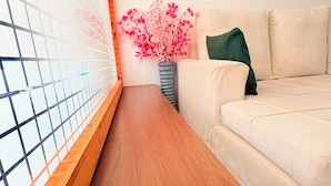 A room with a wooden bench, a beige sofa, a pink flower vase, and a framed quote on the wall. - Cozy one bedroom apartment (Ongata Rongai)