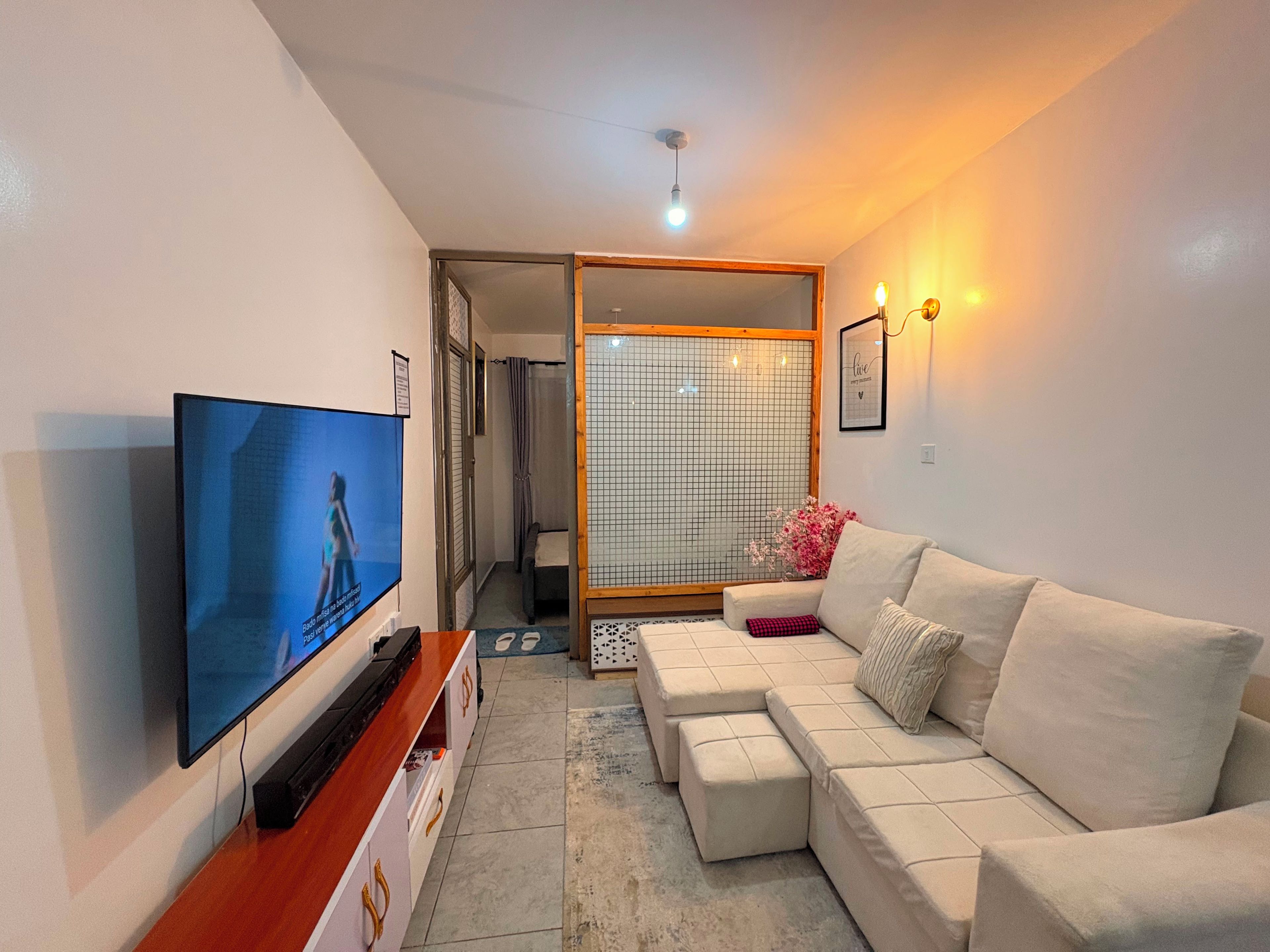 A living room with a flat-screen TV, a beige sofa, and a small table.