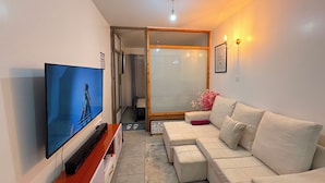 A living room with a flat-screen TV, a beige sofa, and a small table. - Cozy one bedroom apartment (Ongata Rongai)