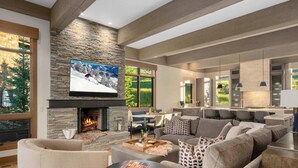 A modern living room with a stone fireplace, a large flat-screen TV, and a cozy seating area. - Abode at White Clouds, hot tub, Sun Valley (Sun Valley)