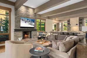 A modern living room with a stone fireplace, a large flat-screen TV, and a cozy seating area. - Abode at White Clouds, hot tub, Sun Valley (Sun Valley)