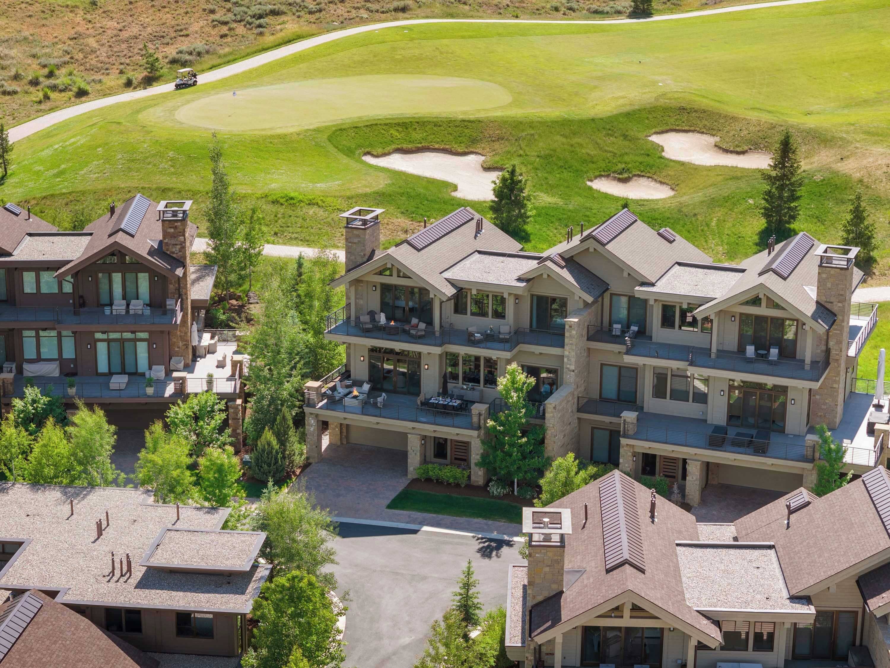 Un edificio residencial de varios pisos con un campo de golf al fondo.